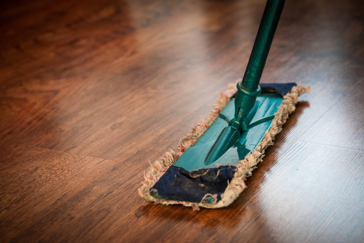 services-01 A detailed view of a mop cleaning a wooden floor, showing texture and pattern.