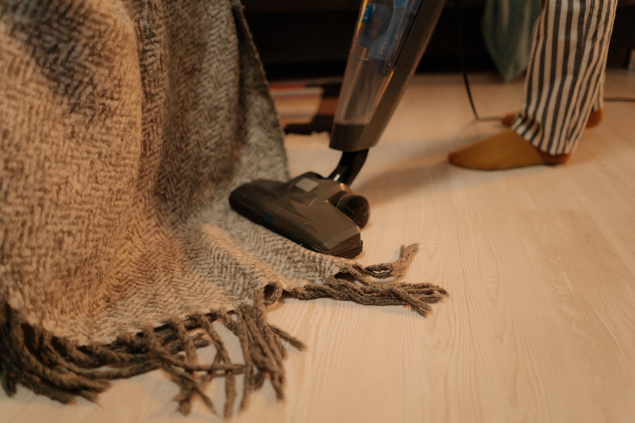 why-choose-us Close-up of vacuum cleaner cleaning a woolen blanket on the floor indoors.